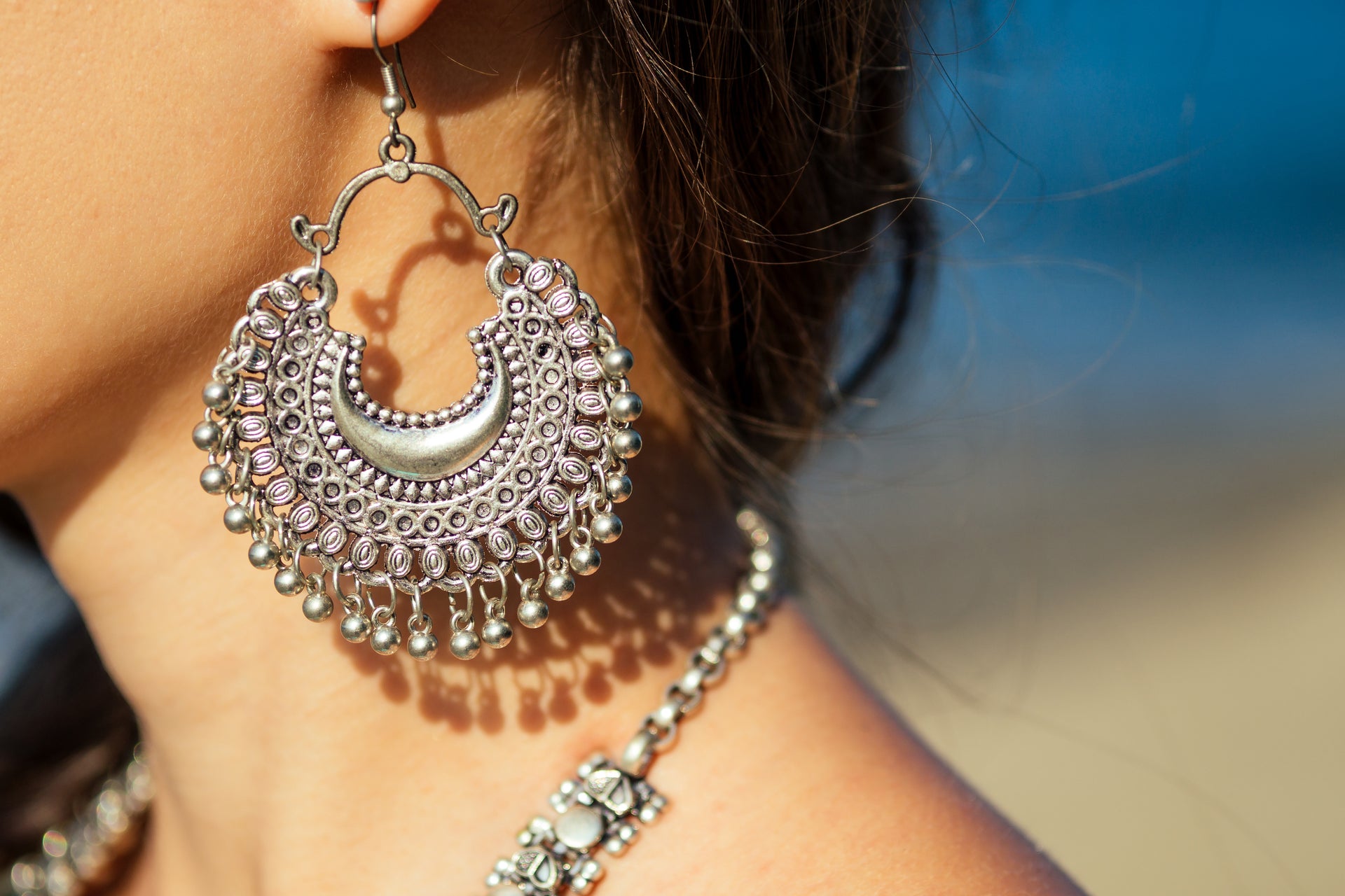 Bohemian-style statement earring handcrafted from recycled metal, featuring intricate detailing and dangling beadwork