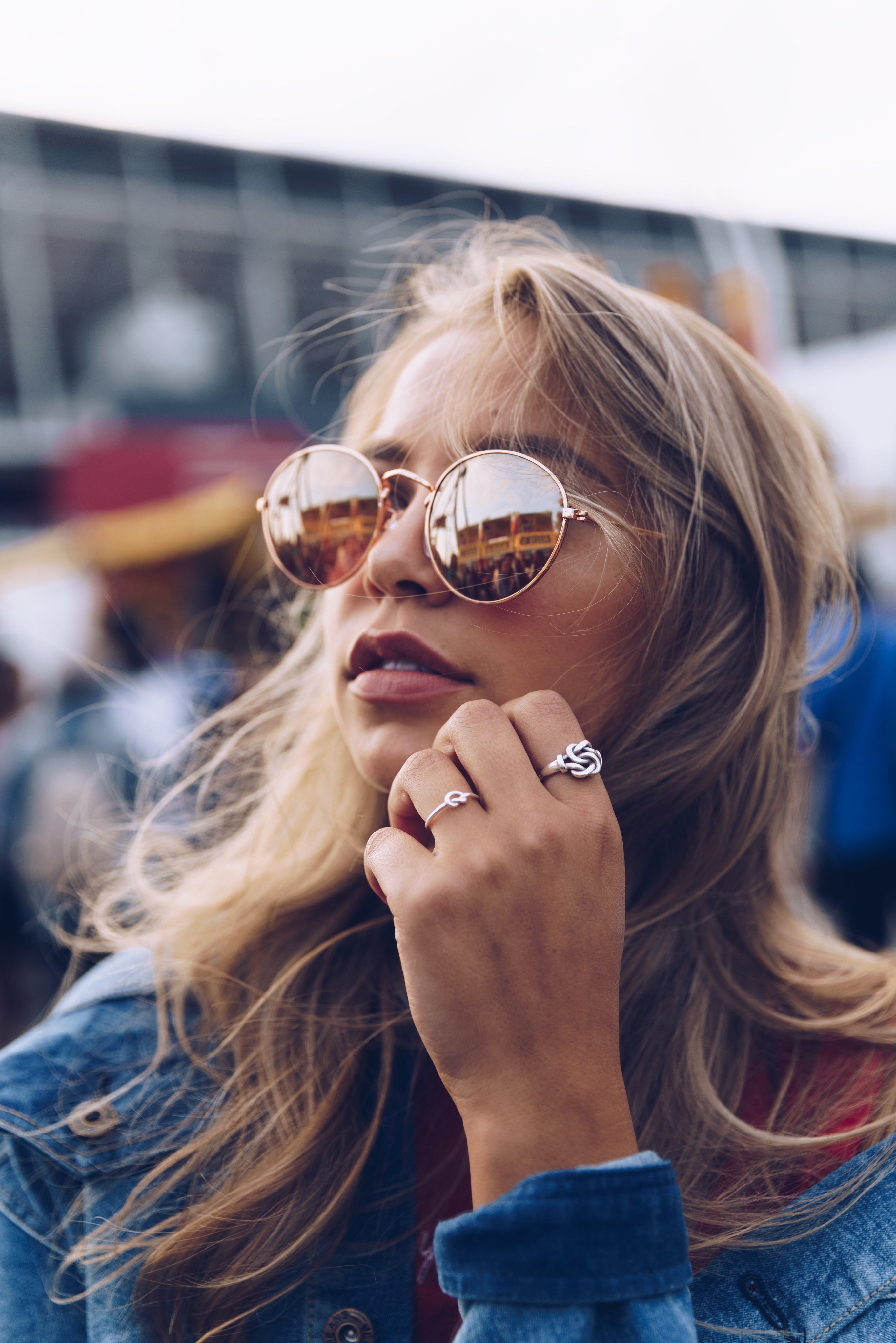 Trendy young woman in mirrored sunglasses and statement rings, showcasing boho fashion accessories and casual street style.